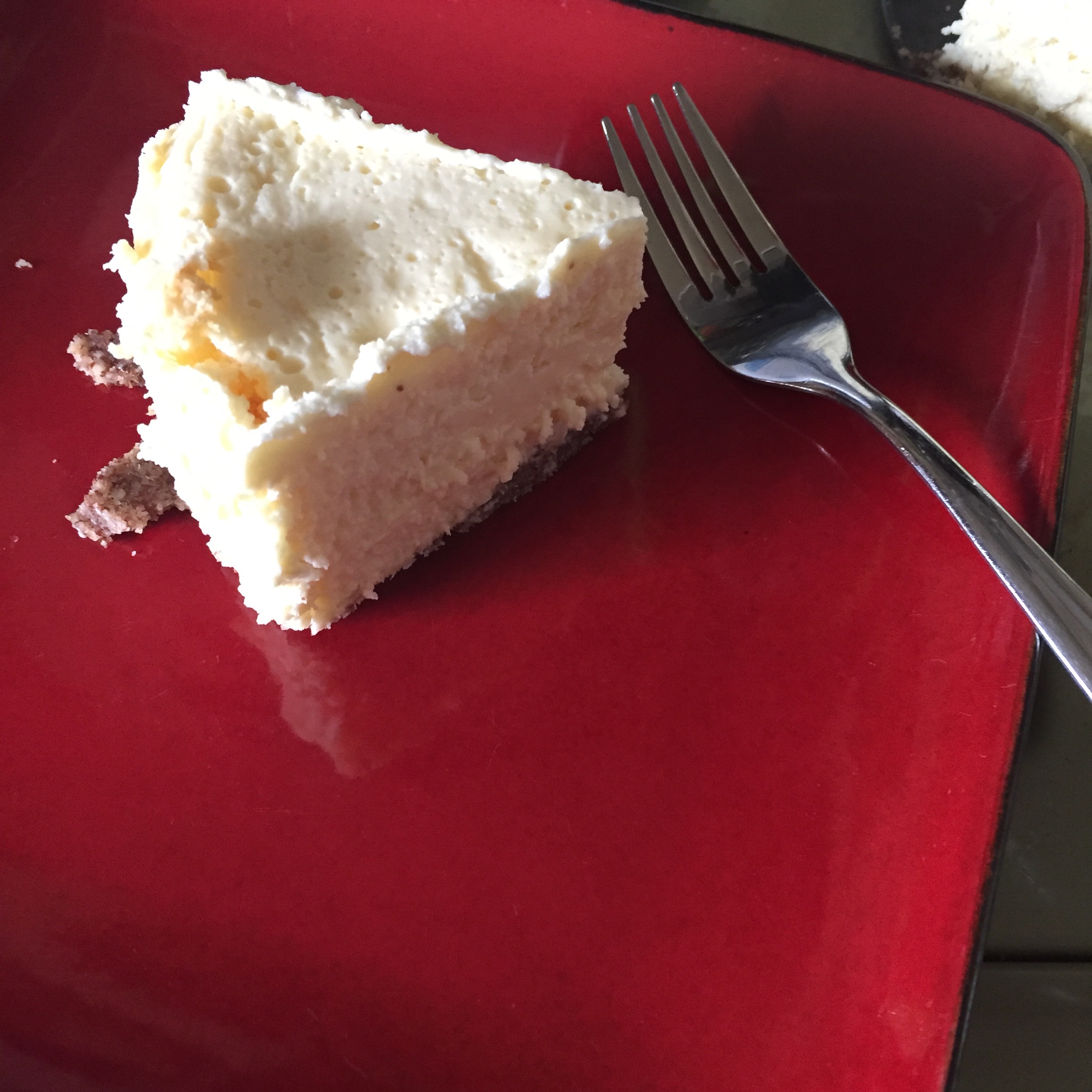 Cheescake slice on red plate with fork