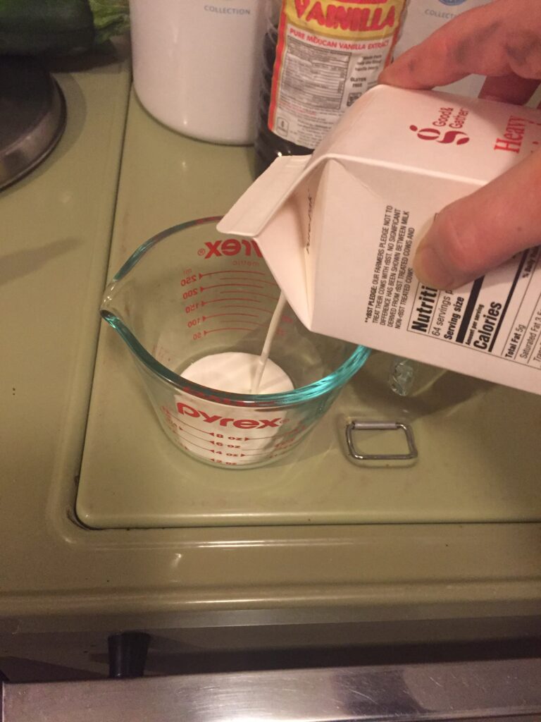 Heavy whipping cream pouring into measuring cup