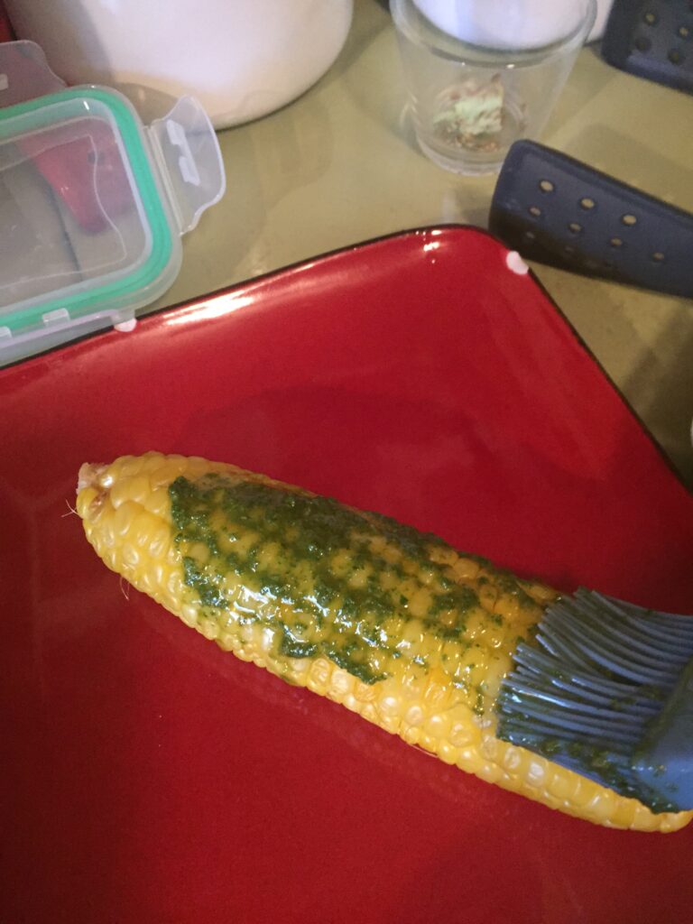 Brushing pesto on corn
