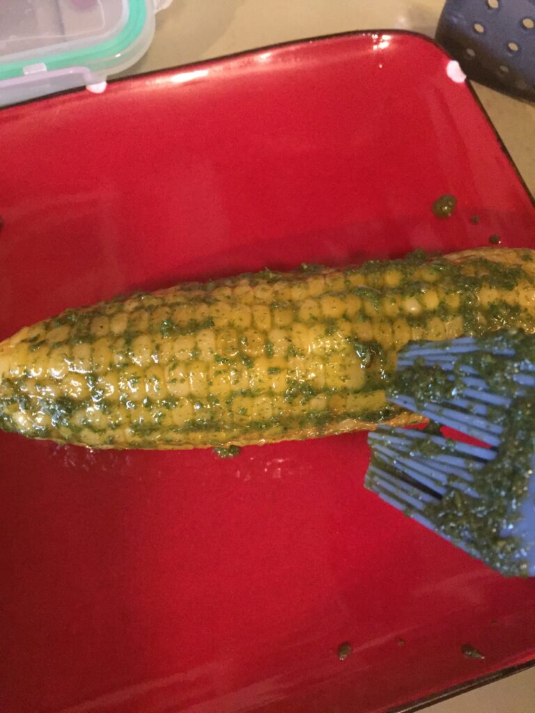 Brushing more pesto on corn on cob