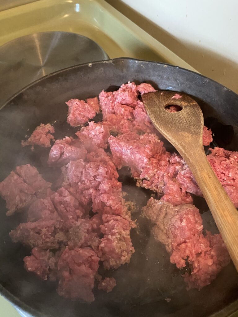 Ground beef browning in cast iron skillet