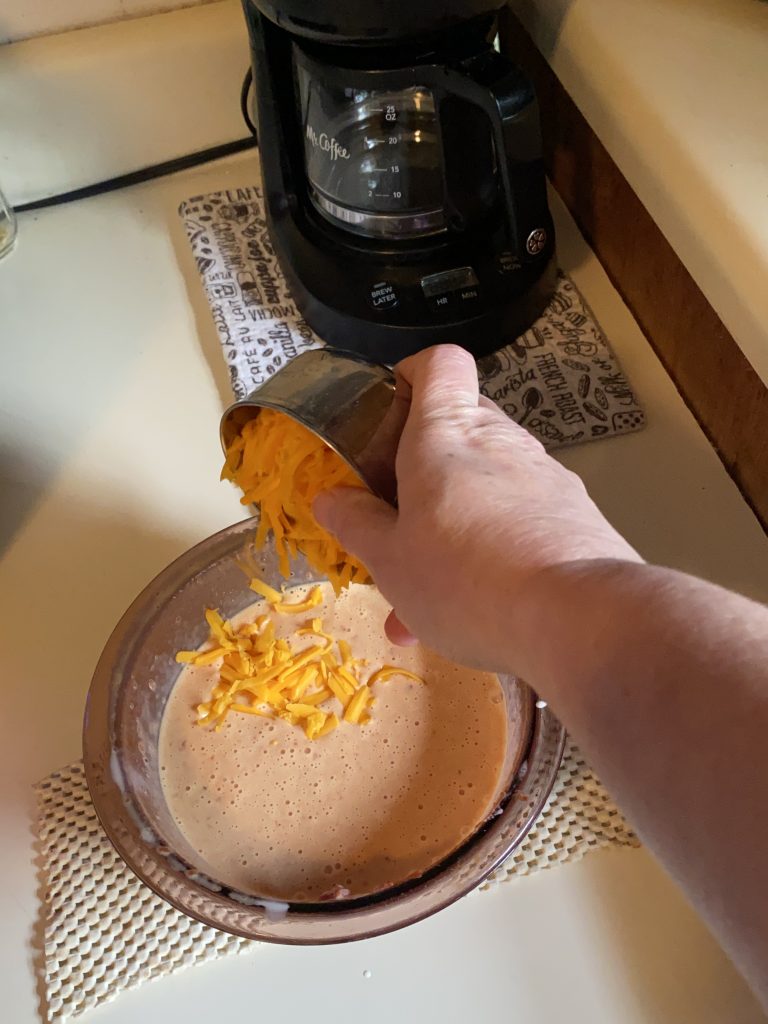 Adding grated cheddar cheese