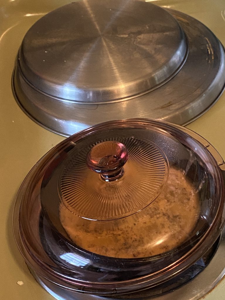 Pan covered on stove cooking eggs