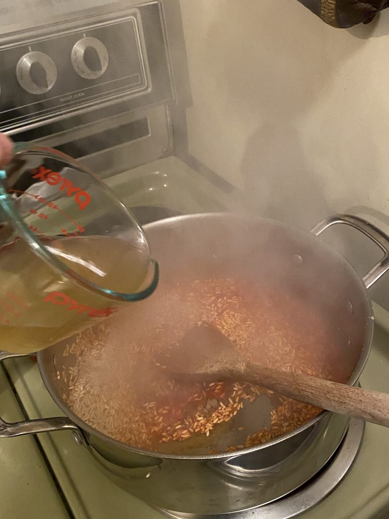 Adding chicken broth to pot