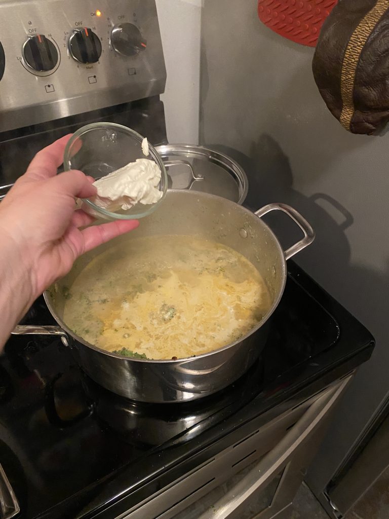 Adding cream cheese to soup pot