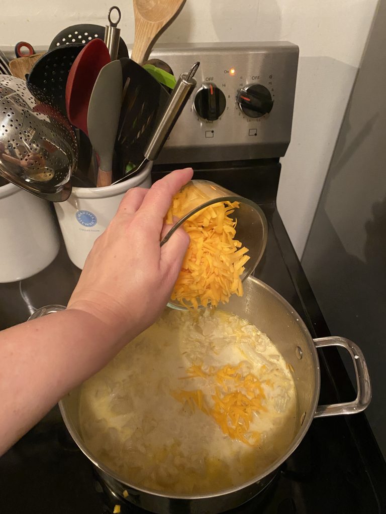 Adding cheddar cheese into soup pot