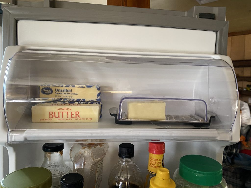 Butter garage in new refrigerator holding butter dish and three sticks of butter