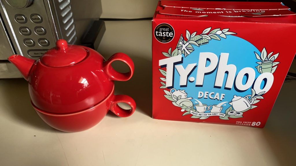 Red tea for one set next to a box of Typhoo Decaf
