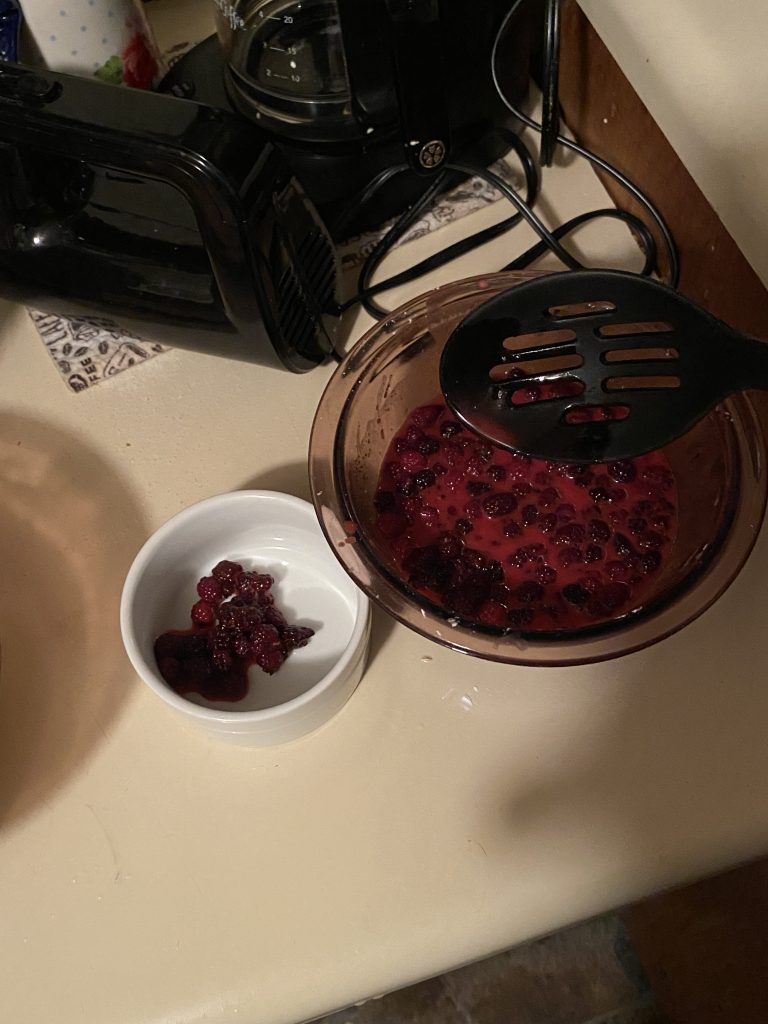 Removing a small amount of blackberries into a small white bowl