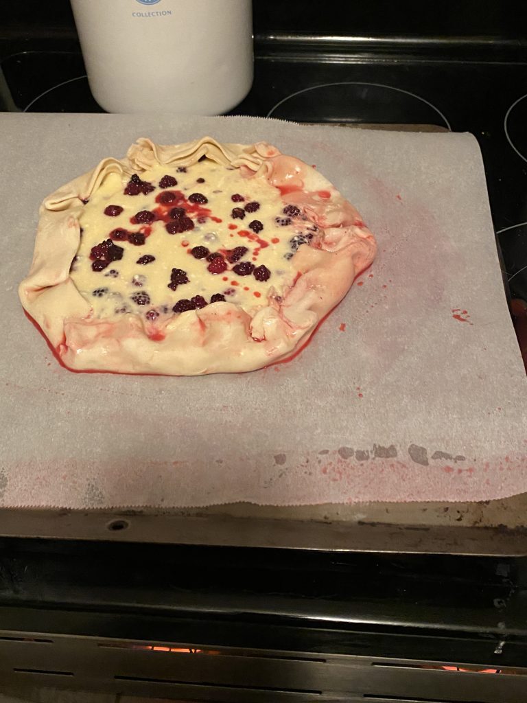 Folded piecrust on blackberry cheesecake galette
