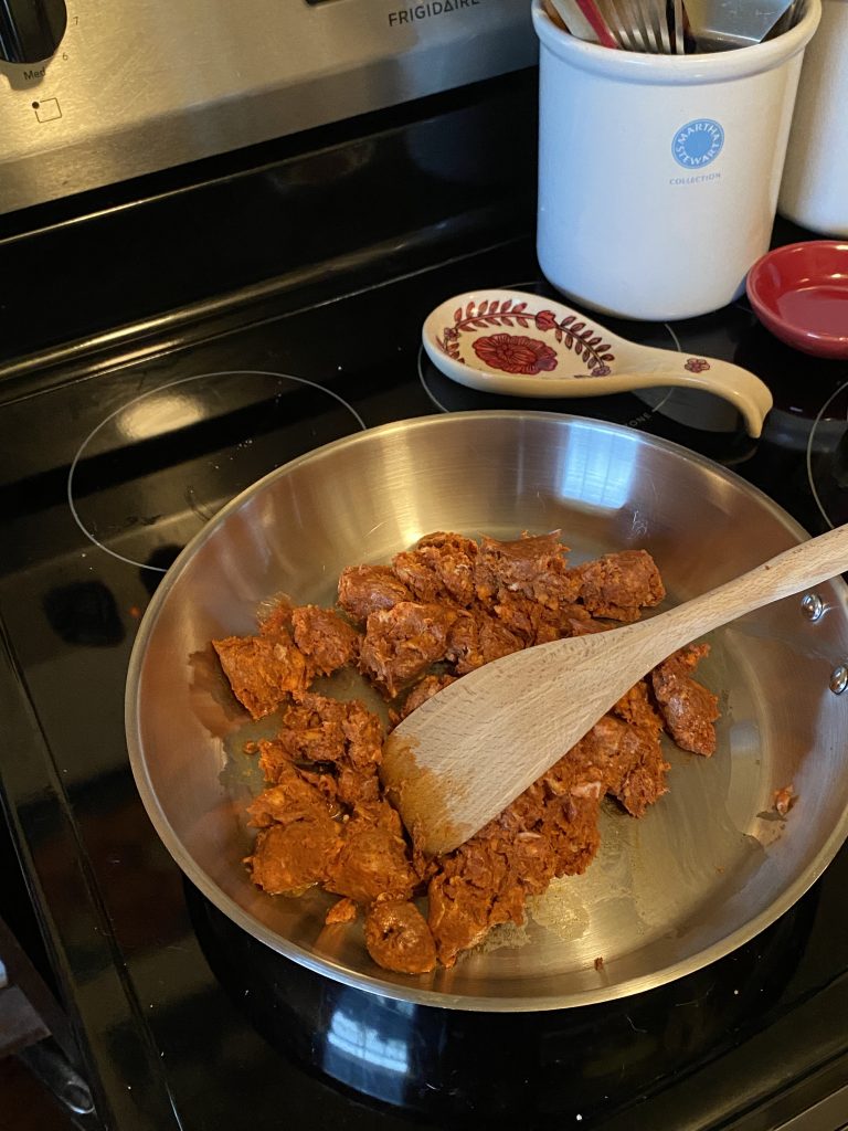 Browning chorizo in a large stainless steel pan