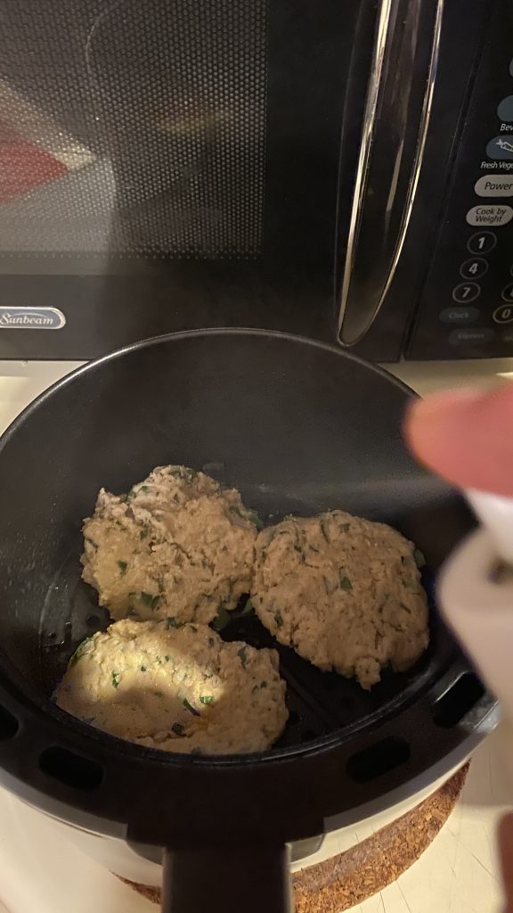 Spraying crab cake patties with oil